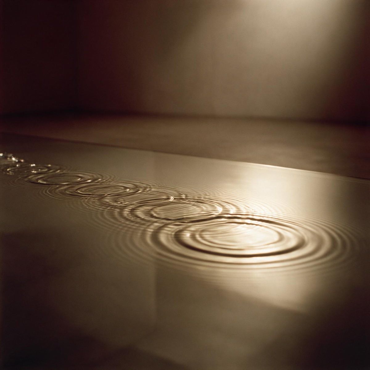 Still water disturbed into slow reflected rings